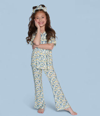 Girl wearing blue and yellow toile floral short-sleeve top and matching flare pants with coordinating headwrap.