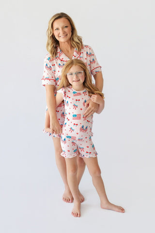 Adult and child wearing matching white short sets with red, blue, and flag print patterns and ruffled hems.