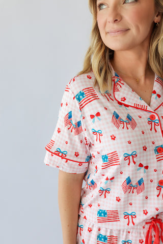 Women's short set with white gingham fabric featuring red, white and blue flags, bows, and floral print throughout.