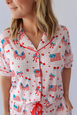 Women's short pajama set with white gingham background, red button front shirt, and patriotic print featuring American flags,