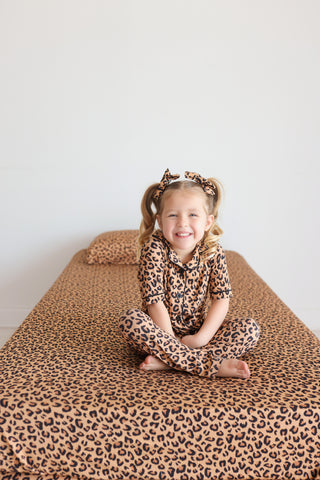 Twin sheet set with tan and black leopard print pattern displayed on bed.