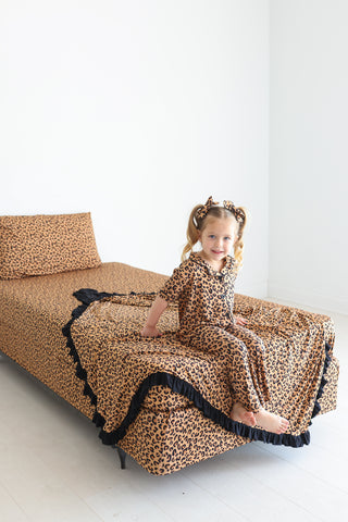 Tan sheet set with black leopard print spots on a twin bed with black ruffle trim.