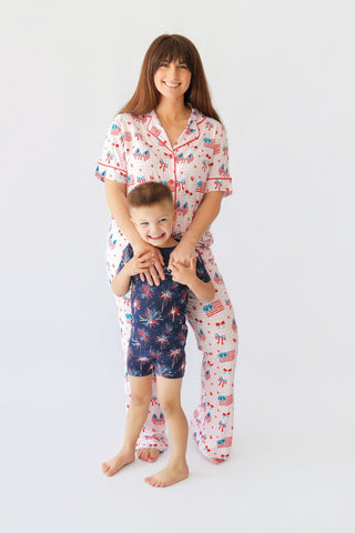 Woman and child wearing matching pajama sets with patriotic flag and fireworks print in red, white, and blue.