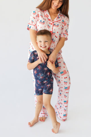 Woman and child wearing matching pajama sets with red, white, and blue patriotic print including flags, fireworks, and bows.