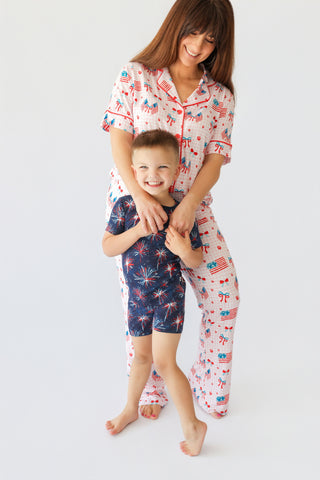 Woman and child wearing matching patriotic pajama sets with flag and firework prints in red, white, and blue.