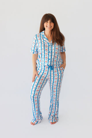 Woman wearing short-sleeve button-up pajama set with blue striped and red floral pattern throughout.