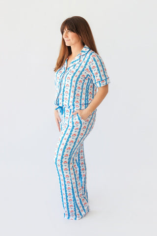 Woman wearing a two-piece pajama set with blue striped and floral print pattern, short sleeves, and flared pants.