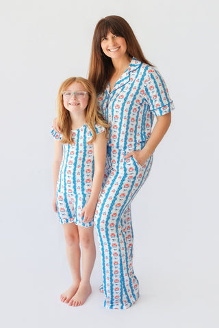Woman and child wearing matching blue and white striped pajama sets with floral print pattern.