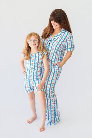 Woman and child wearing matching blue and white striped pajama sets with floral print and bow details.