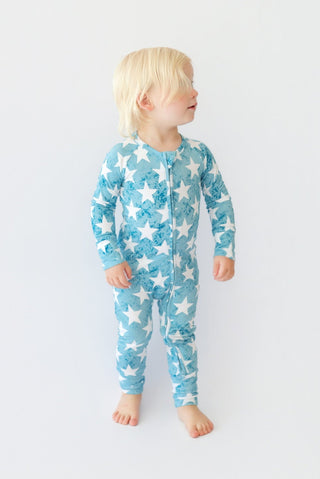 Toddler wearing blue romper with white star print and front zipper.