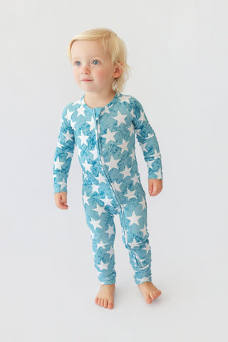 Toddler wearing a teal and white star-patterned long-sleeve romper with front zipper closure.