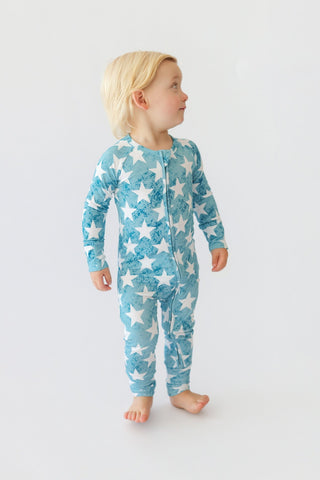 Toddler wearing a blue long-sleeve romper with white star print and front zipper.
