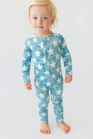 Toddler wearing blue romper with white star pattern and front zipper.