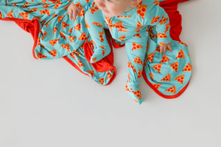 Turquoise romper with orange pizza slice print and red trim on child.