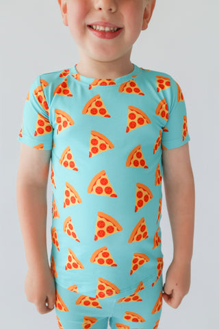Child wearing turquoise short-sleeve shirt with orange and red pizza slice print pattern.