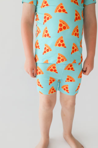 Turquoise short set with orange and red pizza slice pattern throughout shirt and shorts.