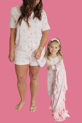 Woman and child wearing matching white short sets with pink floral print and button fronts.