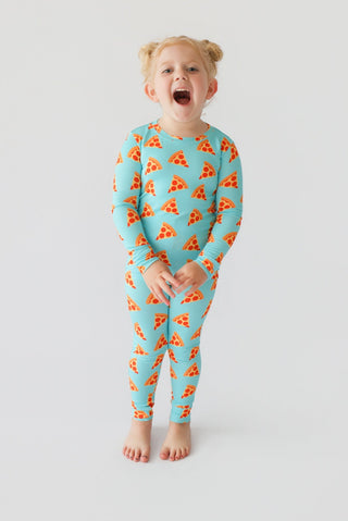 Child wearing turquoise long-sleeve pajamas with orange pizza slice print throughout.