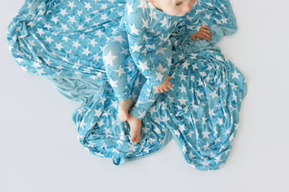 Toddler wearing turquoise romper with white star pattern, long sleeves, and balloon legs, photographed from above.