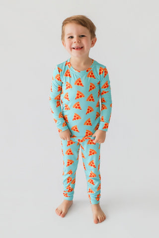 Young child wearing turquoise long-sleeve shirt and matching pants with orange pizza slice pattern throughout.