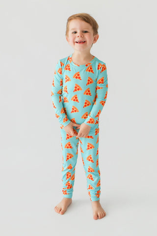 Young child wearing turquoise long-sleeve pajamas with orange pizza slice pattern throughout.