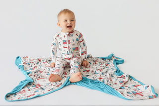 Infant wearing cream romper with red and blue patriotic print and turquoise trim.