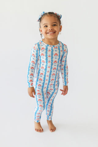 Young child wearing blue and white floral patterned pajamas with matching hair bows.