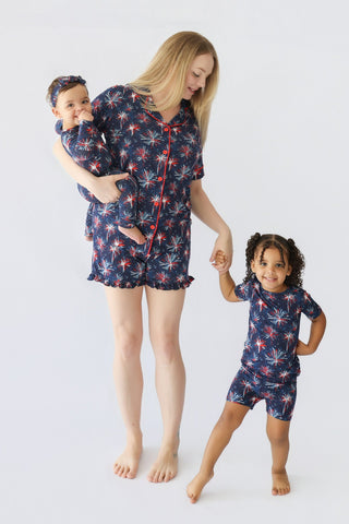 Woman and two children wearing matching navy short sets with red and white firework print patterns.