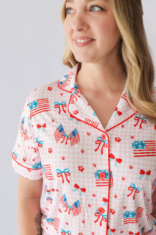 Women's short sleeve pajama top with pink gingham pattern and red, white, and blue flag, bow, and flower print.