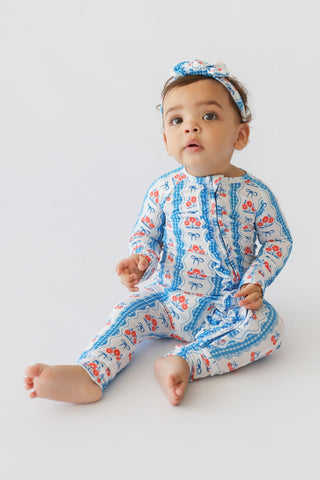 Infant romper with blue gingham and floral print, matching headband with bow, long sleeves and ruffled legs.
