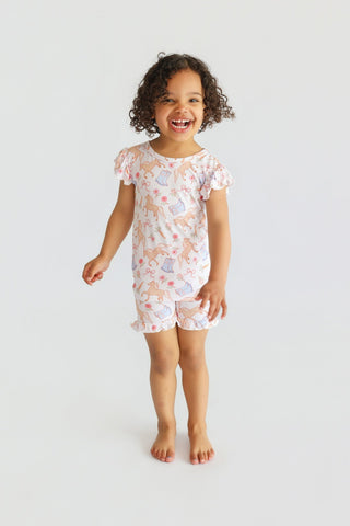 Child's two-piece pajama set with short sleeves and shorts featuring boots and floral print pattern.