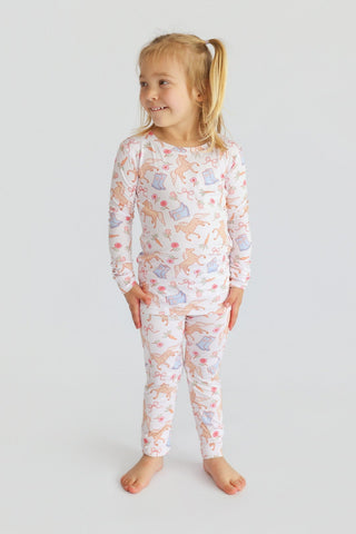 Young child wearing cream pajamas with pink and peach boot and floral print throughout long-sleeved top and pants.