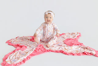 Infant in pink floral romper with ruffle trim and matching headband, displayed flat on white background.