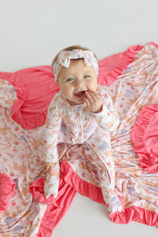 Infant wearing floral print romper with pink ruffled trim and matching bow headband.