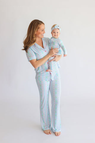 Woman and infant wearing matching light blue pajama sets with multicolored tulip print and flared pants.
