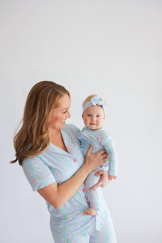 Woman holding infant, both wearing matching light blue flare pajamas with tulip pattern and coordinating headband.