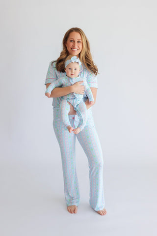 Woman and infant wearing matching light blue and pink tulip-patterned pajama sets with flared pants and headbands.