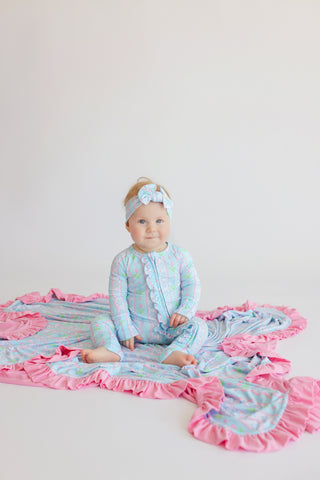 Baby wearing light blue romper with tulip print and pink ruffled trim, matching headband included.