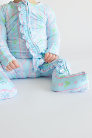 Light blue romper with pink and green floral print, front zipper, and matching booties with pink trim.