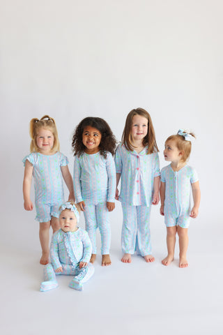 Five young children wearing matching light blue and pink tulip-patterned short-sleeve pajama sets.