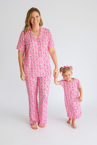 Woman and child wearing matching pink pajama sets with ribbon and lantern print, short sleeves, and flared pants.