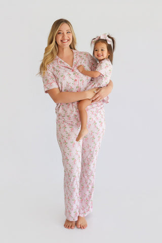 Woman and child wearing matching pink floral pajama sets with short sleeves and flared pants.