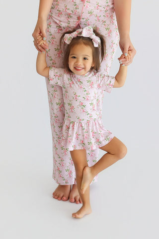 Young child wearing pink floral bow hair clips while being held by an adult in matching floral outfit.