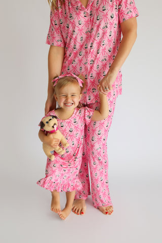 Adult and child wearing matching pink pajama sets with ribbon and carousel horse pattern.