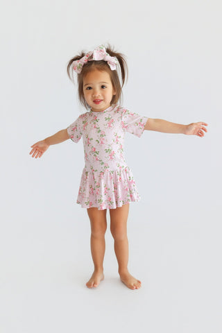 Pink floral bow hair clips with green leaf pattern worn on child's pigtails.