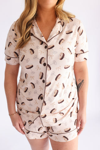 Cream short pajama set with brown martini glass and bow print, button-up shirt with notch collar and piping trim.