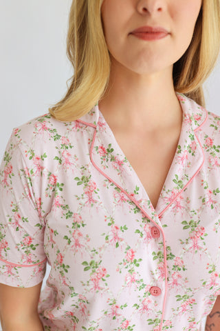 Women's short-sleeve button-front top with pink floral print and matching pink trim on white background.