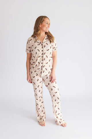 Woman wearing beige pajama set with brown martini glass print, short sleeves, and flared pants.