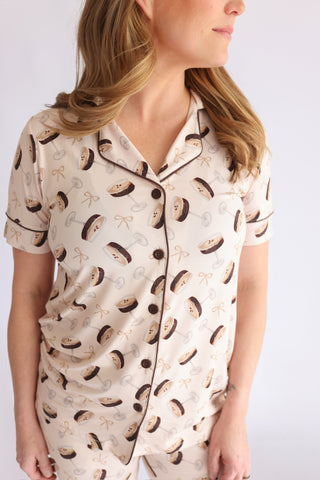 Cream short-sleeve pajama top with martini glass and bow print, button front, and dark piping trim.