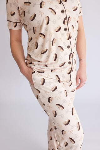 Cream pajama set with martini glass and bow tie print, short-sleeved top and flared pants with button front.